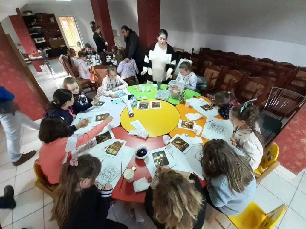 Copii ucraineni și români învață împreună să picteze icoane pe sticlă în Huedin